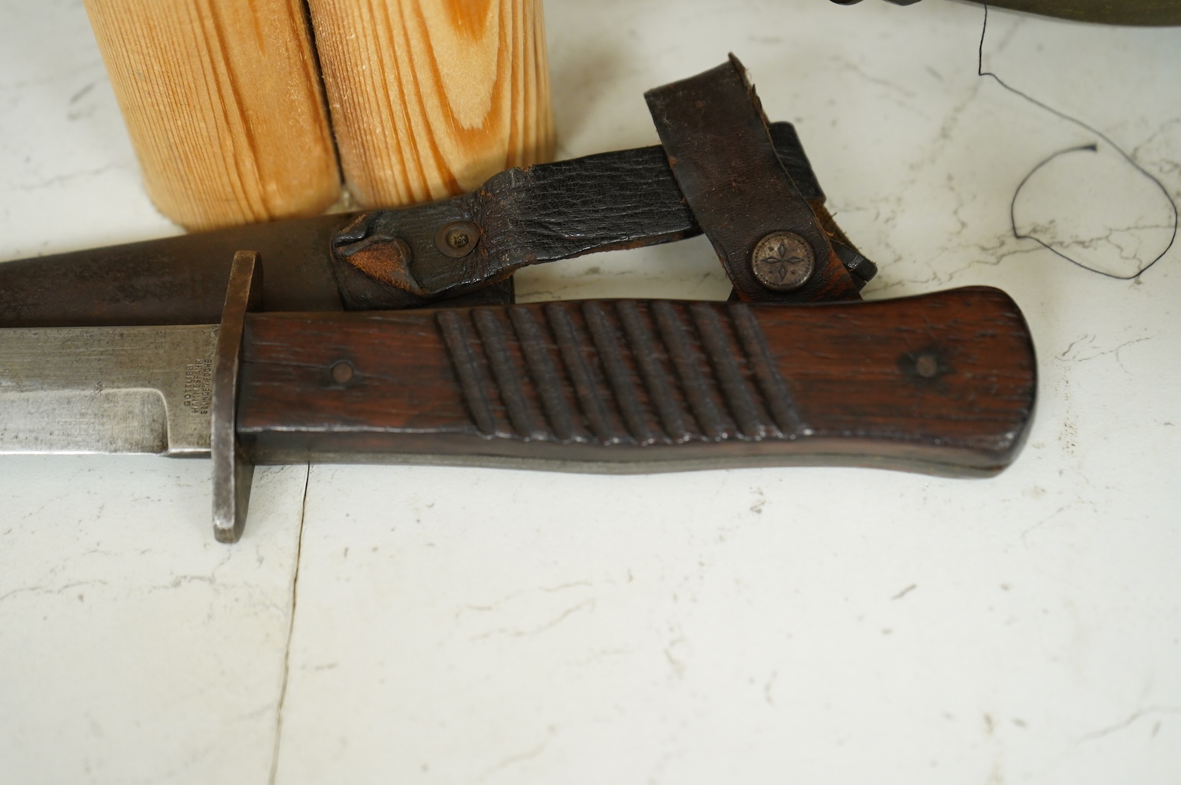 A First World War German Fighting Knife, with two piece wooden grip and steel cross guard, in original steel scabbard with leather belt loop mount, single edged blade with makers mark to one side; Gottlieb Hammesfahr, So
